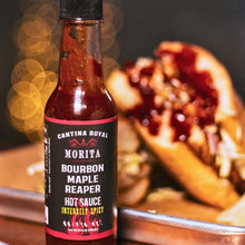 A pivture of Morita Bourbon Maple Reaper Hot Sauce in front of a pulled pork sandwich covered in Moritahot sauce